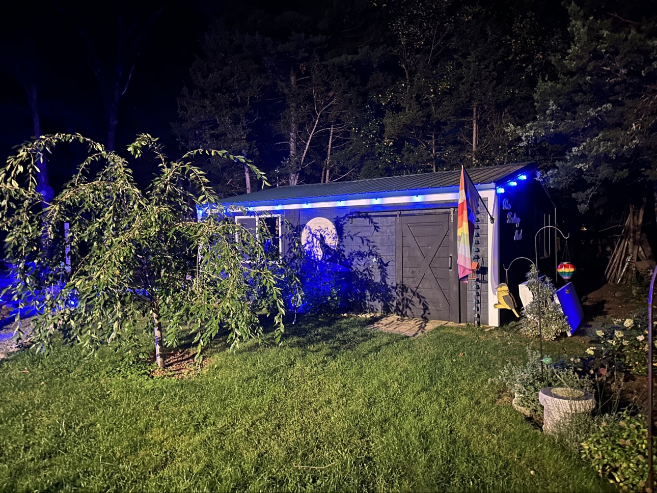 The Healing Shed at night with blue lights and the moon painting